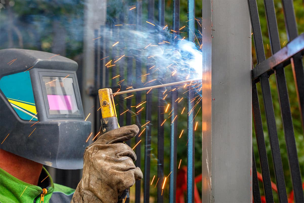 A Professional Worker Welds A Fence
